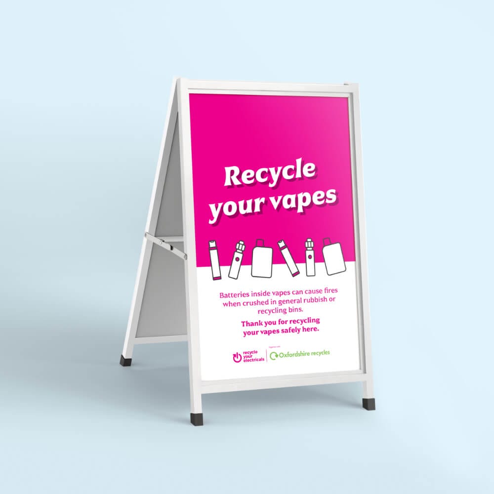 A-frame sign in pink and white against a pale blue background, text on sign: Recycle your Vapes