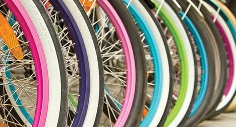 close up of many brightly coloured bicycle wheels in a row