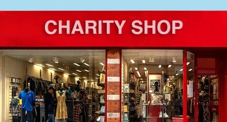 Shop front window of a red shop with a 'Charity Shop' sign.