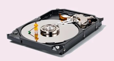 a close up of a hard drive with the casing open and a tiny figure with a broom sweeping the hard disk itself