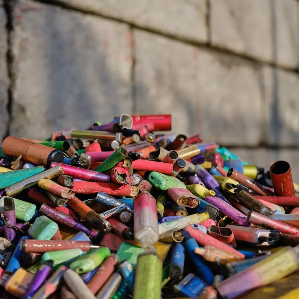a large pile of discarded single use vapes on the ground
